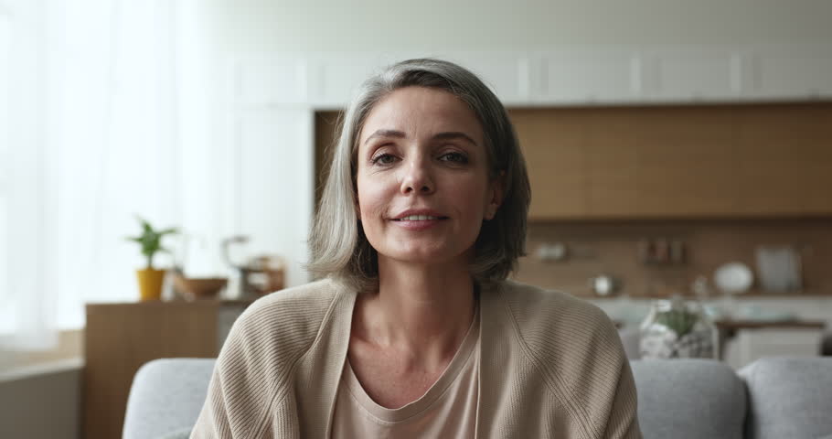 Positive pretty grey haired woman talking on video conference call, listening, nodding, speaking, laughing, explaining with hand gestures, enjoying Internet communication. Head shot portrait