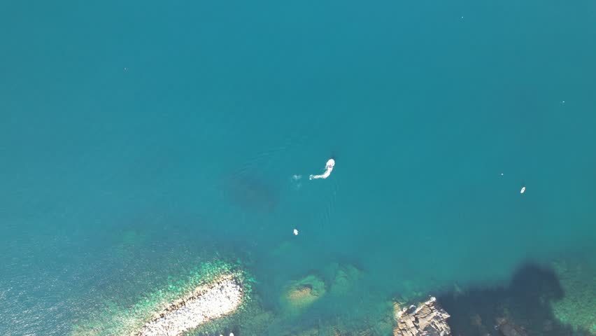 A drone shot looking down on a boat circling the Mediterranean Sea, Capri, Italy