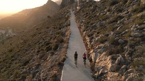 Sunset Ride.Two cyclists enjoying a scenic route along an empty mountain road in Spain with stunning views of the sunnset and mountains. Aerial drone video, follow shot. Alicante, Costa Blanca, Calpe