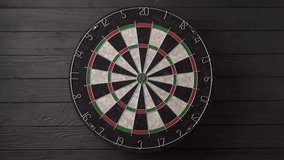Three darts are aimed and thrown by hand and hit the dartboard on a black wooden background. Lucky - one of the darts hits the bull's eye. The concept of winning and luck - Powered by Shutterstock - Get 15% off with code: PIKWIZARD15
