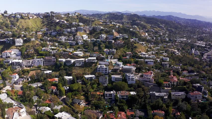 Wide descending aerial shot of homes perched on the hillside above the Sunset Strip in Beverly Hills, California. HD at 60 FPS