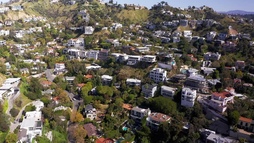 Wide rising and panning aerial shot of homes on the hills above the Sunset Strip in Beverly Hills, California. HD at 60 FPS