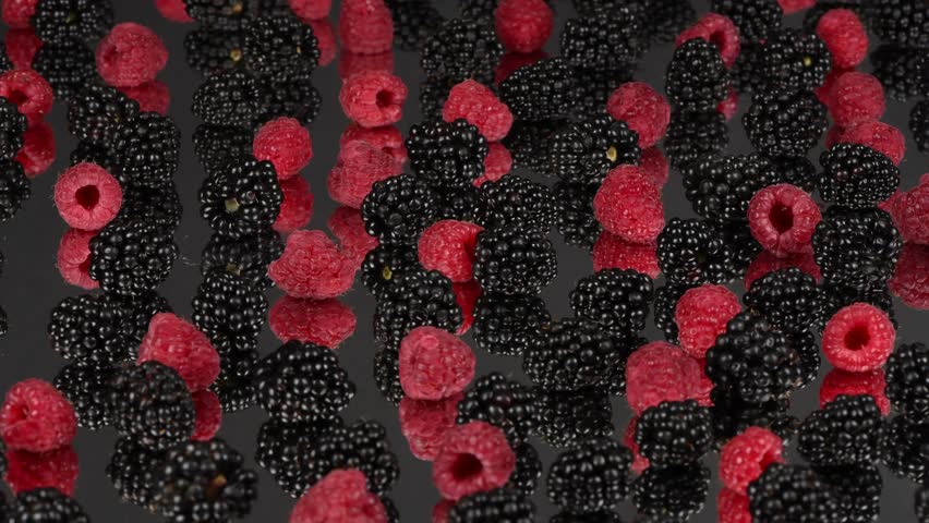 Blackberry and raspberry with reflection on black background. Side view. Loop motion. Rotation 360. 4K UHD video footage 3840X2160.