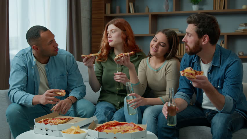 Group of friends colleagues eat pizza talk happy diverse women and men drink beer celebrate event party guys and girls meeting in living room order lunch food delivery at home multiracial friendship Royalty-Free Stock Footage #1102390905