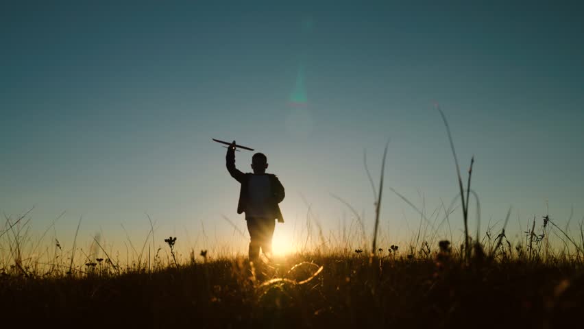 Child boy wants to become pilot astronaut, Airplane flight. Happy Child boy plays with toy plane on field, sunset. Children play with toy airplane. Teenager dreams of flying, becoming pilot. Childhood