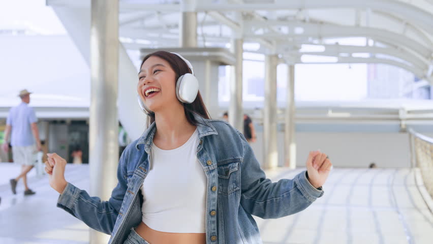 Young asian woman using headphone for listening nice music and walking in city. Girl happiness, smile face. Female love listen music that make her relax and enjoying life Royalty-Free Stock Footage #1102399883