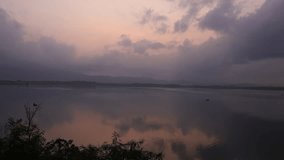 Video background of morning nature around a reservoir or large lake, wind blowing, cloud streaks and rising sun in a beautiful ecological mountain landscape.