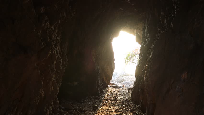 Video background of the sunlight shining through the cave or under the rock by the sea, a beautiful nature adventurous journey.