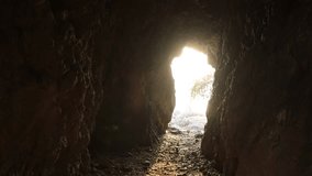 Video background of the sunlight shining through the cave or under the rock by the sea, a beautiful nature adventurous journey.