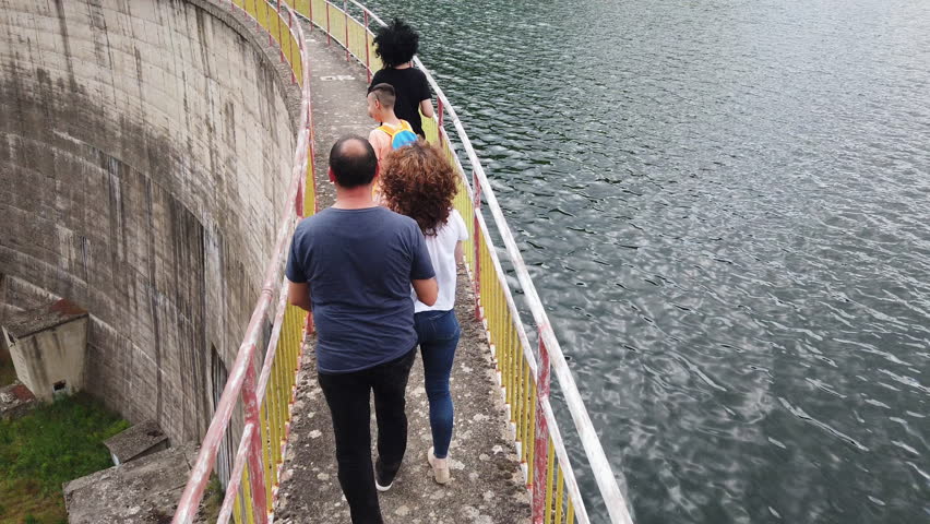 Slow motion of a family walking on a bridge on hydroelectric dam