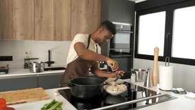 Young african man preparing fried chicken mince with vegetables recipe in a kitchen.