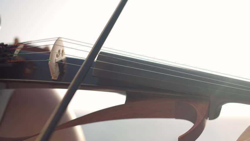 Close-up violin fretboard in sunbeam with female fingers touching strings playing music with bow. Unrecognizable Caucasian talented woman performing in sunshine outdoors closeup Royalty-Free Stock Footage #1102409503