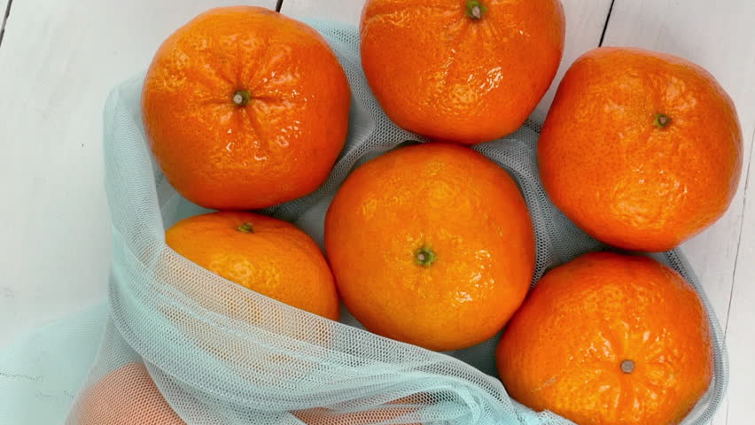 Ripe juicy tangerines in eco-friendly grid rotate on white background. Royalty-Free Stock Footage #1102409629