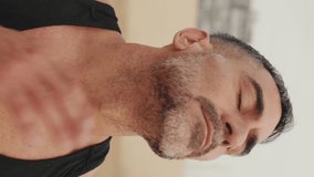 Vertical video, Close-up of mature man stretching his neck muscles while standing on the beach in the morning