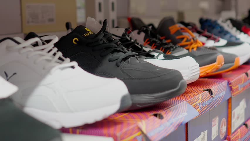 Shop display of lot of Sports shoes on wall. View of wall of shoes inside store. Modern new stylish sneakers for men and women. Camera movement on showcase with sneakers.