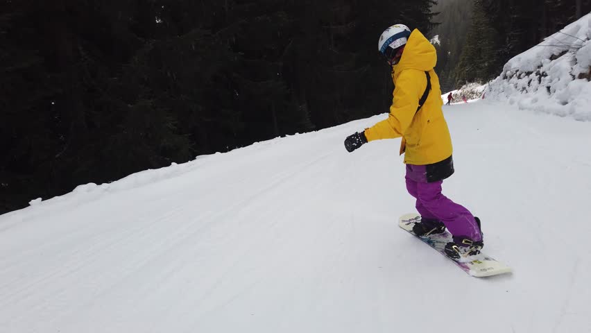 girl in yellow snowboarding in alps YL