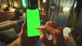Close up man holds a scrolling phone with a vertical green screen in a dark room. Device. Smartphone. Social media - Powered by Shutterstock - Get 15% off with code: PIKWIZARD15