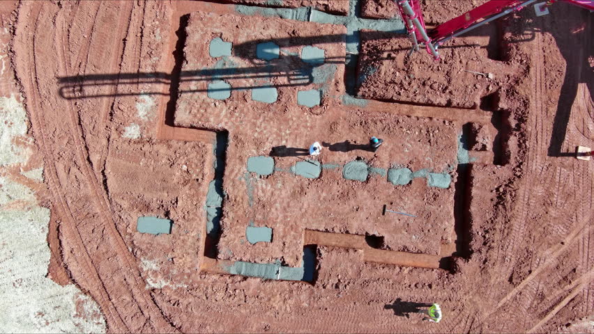 Pouring cement concrete for foundation of house using an automatic pump to direct concrete.