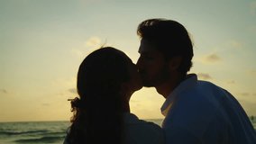 Silhouette shot, Young latin male standing on the beach looking and kissing with his girlfriend in sunset background, They spending time together during summer vacation or honeymoon trip. - Powered by Shutterstock - Get 15% off with code: PIKWIZARD15