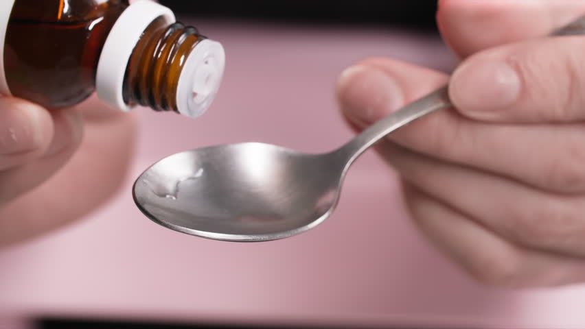 sedative drops, woman holds bottle of medicine in her hands and drips into spoon from a dispenser, close-up