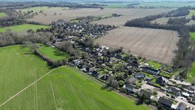 A drone flies over the Kent village of Nonington, providing a stunning view of the village from a unique perspective on a sunny day with blue skies and green fields.