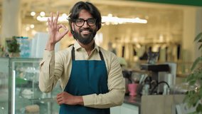 Portrait smiling happy small business owner Indian Arabian man Muslim cafe worker posing in cafeteria with ok gesture ethnic male waiter smile showing okay symbol sign guy good fine coffee service - Powered by Shutterstock - Get 15% off with code: PIKWIZARD15