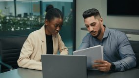 Diverse Indian Arabian man and African American woman colleagues discuss financial data analyzing documents marketing project result in report use laptop talk business conversation sit at office desk - Powered by Shutterstock - Get 15% off with code: PIKWIZARD15