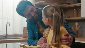 Cute little Caucasian girl child kid cooking veggie salad mix vegetables with spoon cook healthy vegetarian food at home kitchen father hugging cuddling daughter touch nose happy family relationships - Powered by Shutterstock - Get 15% off with code: PIKWIZARD15
