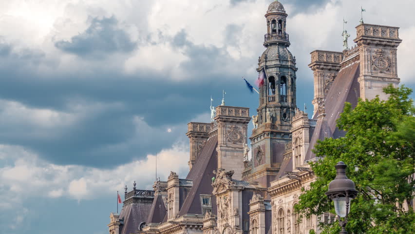 Architecture of The Hotel de Ville City Hall with french flag on tower top timelapse, the building housing the local administration of the city of Paris. Cloudy sky at summer day. Close up view