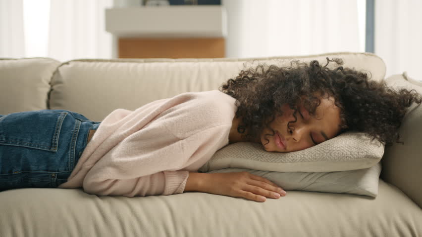Depression concept. Tired girl lying asleep feeling out of energy motivation. Exhausted tired lazy young african american woman falls down on sofa. Apathetic bored lady sleeping on couch at home alone | Shutterstock HD Video #1102434693