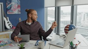 Contemplative designer looking solution at home office close up. Pensive man holding graphic tablet thinking at remote workplace. Hipster freelancer pondering fresh ideas at city view apartment alone - Powered by Shutterstock - Get 15% off with code: PIKWIZARD15