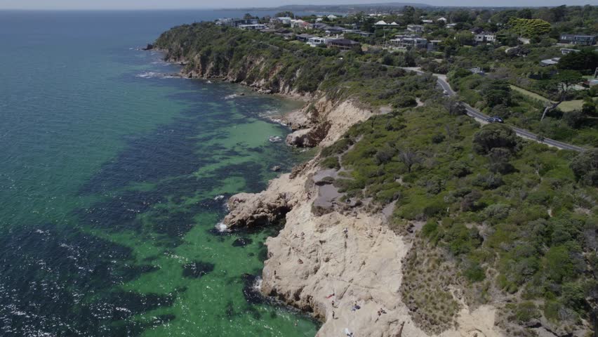 Tourists Sunbathe On The Rocky Cliffs At The Mount Martha Pillars In Melbourne, Australia. Aerial Drone Shot
