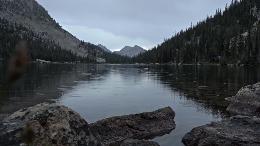 View across backcountry mountain lake as gentle rain falls on water surface