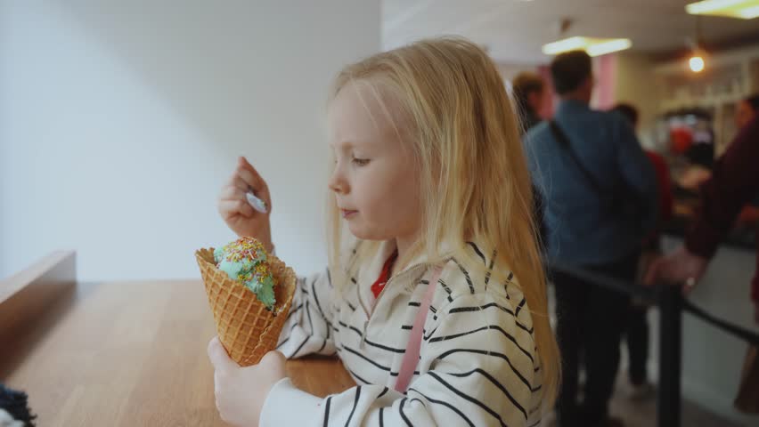 A cute girl is eating ice cream in a cafe. Ireland. Kilkenny 2023