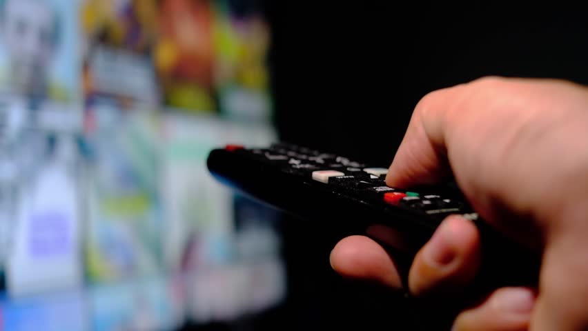 Man's hand holding a remote control, multimedia, online TV, broadcasting entertainment to viewers at home. The idea behind the broadcast | Shutterstock HD Video #1102444547