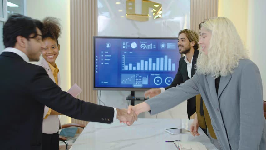 Smiling office workers meeting in office. Cheerful business partners or client making deal walk in over and shake hands greeting each other in conference room. Business meeting and brainstorming 