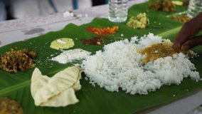 People eating traditional Indian wedding marriage sadhya rice Sambar parippu dal curry ghee Payasam on banana leaf. Onam Vishu Pongal Diwali festival vegetarian food Kerala Tamil Nadu South India.