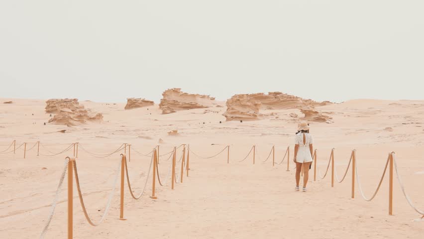 Female tourist visit walk around Fossil Dunes Structures. Abu Dhabi, UAE. Natural wonder formed desert sculptures crafted from wind-swept, calcium-carbonate-infused sand