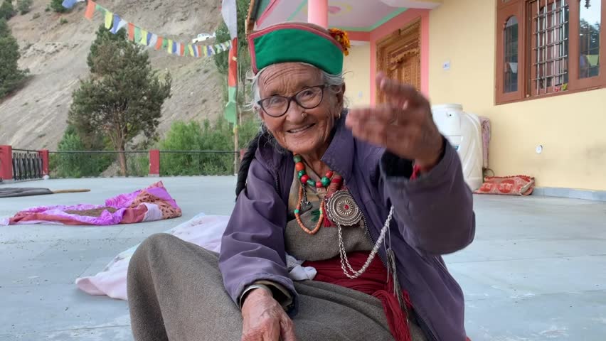 A happy grandmother waving hand and enjoying work in a Himalayan village of India. Grandmother wearing traditional attire. Royalty-Free Stock Footage #1102449097