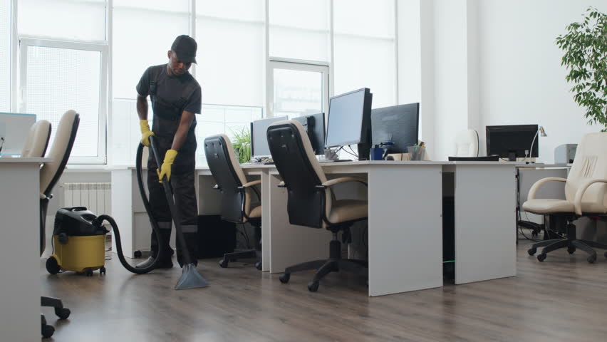 Slow motion long shot of young Black man and Caucasian woman in uniform cleaning modern open plan office Royalty-Free Stock Footage #1102449255