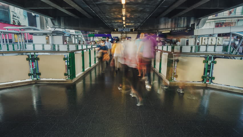 Moving people on BTS skytrain station in Bangkok city time lapse. Motion of busy crowd of people in the evening in the skybridge. Long exposure Royalty-Free Stock Footage #1102451717