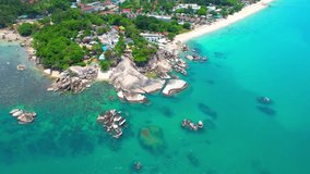The rocks are located on a picturesque beach surrounded by clear blue waters and towering palm trees. From above, the view of the beach and the rocks is stunning. (Koh Samui, Thailand). 4K HDR
