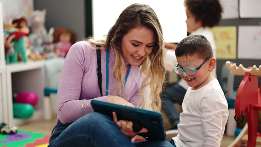 Woman and boy having lesson using touchpad at kindergarten
