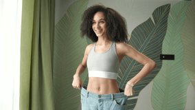 Happy Woman After Weight Loss. Mixed race slim female wearing oversized jeans. Successful weight loss. - Powered by Shutterstock - Get 15% off with code: PIKWIZARD15