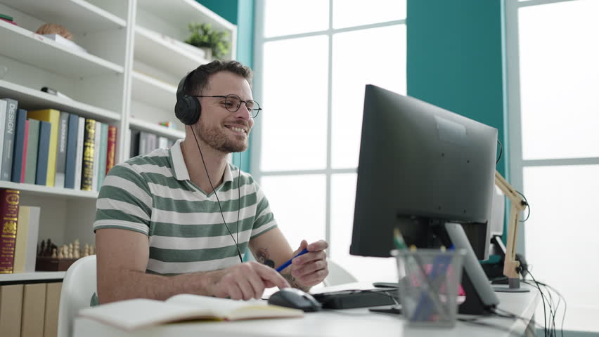 Young caucasian man student using computer taking notes at library university
