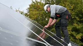 Man technician mounting photovoltaic solar panels on roof of house. Engineer in helmet installing solar module system with help of hex key. Concept of alternative, renewable energy. - Powered by Shutterstock - Get 15% off with code: PIKWIZARD15