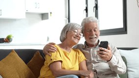 Happy retired family couple using mobile phone for video call together, talking to relations, getting good news, having fun, smiling and laughing. Carefree mature pensioners chatting online on cell

