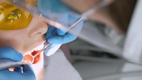 Dentist woman treats teeth of young female patient in clinic. Dentist wears face mask when using dental drill and polishing teeth. dental procedures in modern dentist's office. Latex napkin. rubber.