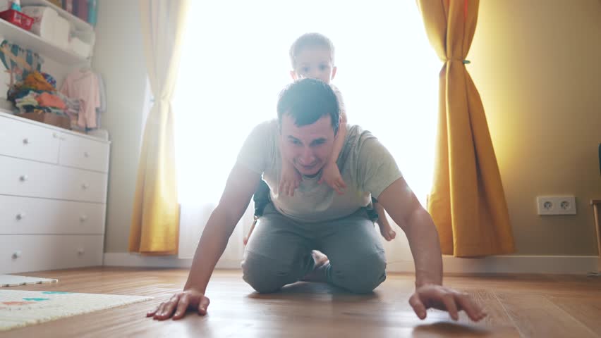 dad playing with baby at home. happy family kid dream concept. dad plays with his son baby rolls her on his back kneels on floor fun funny. baby and dad play at home lifestyle Royalty-Free Stock Footage #1102464745