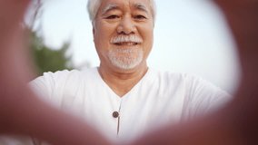 Portrait of Happy Asian senior man showing hands heart shape during walking at tropical beach at summer sunset. Retired elderly people enjoy outdoor lifestyle travel nature ocean on holiday vacation. - Powered by Shutterstock - Get 15% off with code: PIKWIZARD15